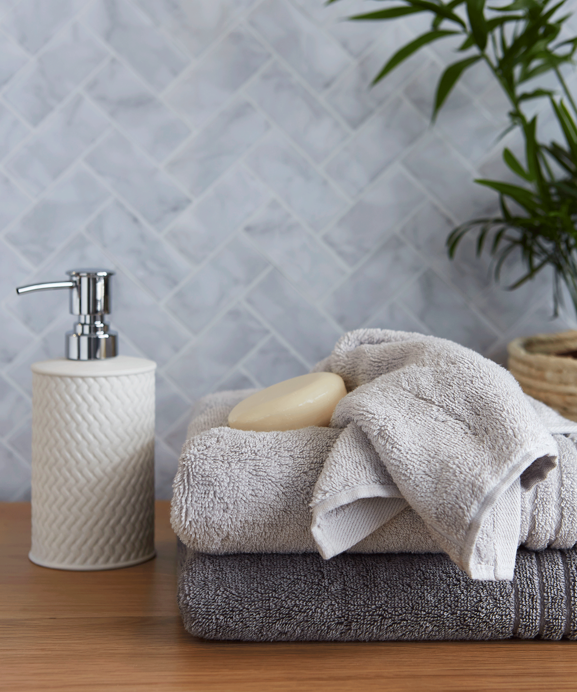 Dunelm towels and soap dispenser in a grey tiled bathroom