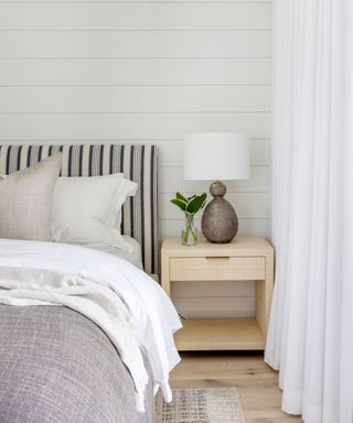 white bedroom with panelled walls and striped headboard