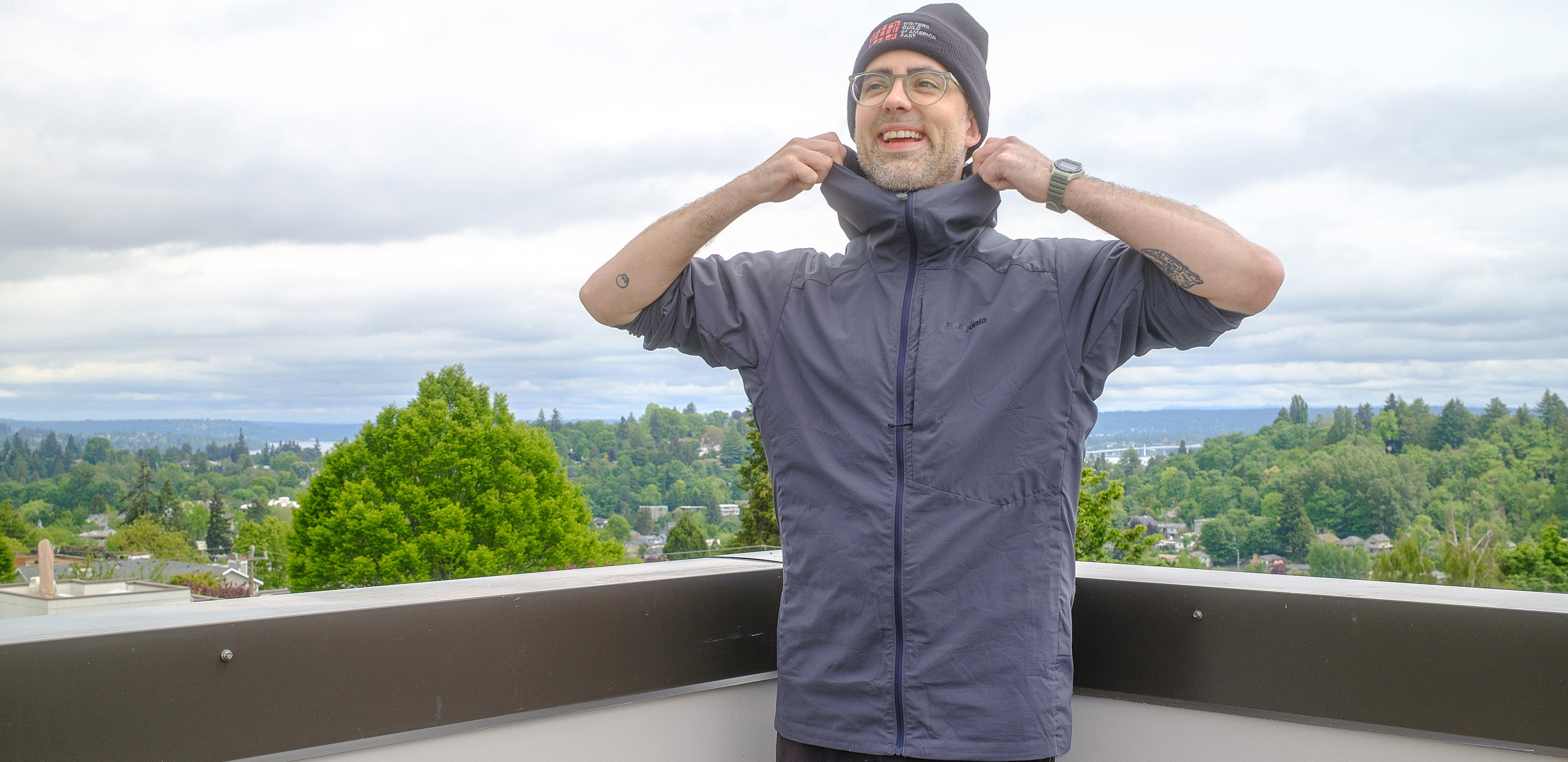 Senior writer Dan Bracaglia wearing the Patagonia Nano-Air Ultralight in grey/blue on the roof of his home in Seattle, Washington with trees and overcast skies in the distance