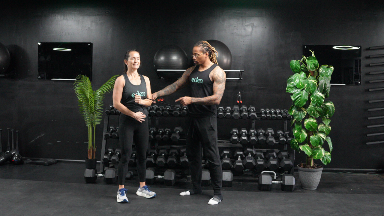 NASM-certified personal trainer Brandon Polk coaches a female client through internal and external shoulder rotations with a resistance band