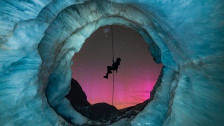 I originally found this ice cave, called a moulin, 8 months prior to setting up this shot in Aoraki/Mount Cook National Park. Glaciers are a very dynamic environment, so I kept going back to monitor the changes of this moulin over the 8-month period. As the opening of the cave formed, I envisioned setting up a night shot with my friend abseiling down the mouth of the cave with New Zealand&rsquo;s amazing starry sky in the background.One magical night, everything finally came together! To my surprise, the Aurora Australis also lit up the sky. I managed to capture my friend&rsquo;s silhouette perfectly placed in the center of the cave&rsquo;s opening, and I love how the pinky tones of the aurora contrast with the icy colors of the cave. This dream shot ended up coming out better than I had originally envisioned, and I had a great night with my friends exploring the glacier!