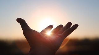 A hand reaching towards the sunset