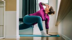 Woman at home practicing yoga. She is in low lunge with her torso twisted so she looks at the ceiling