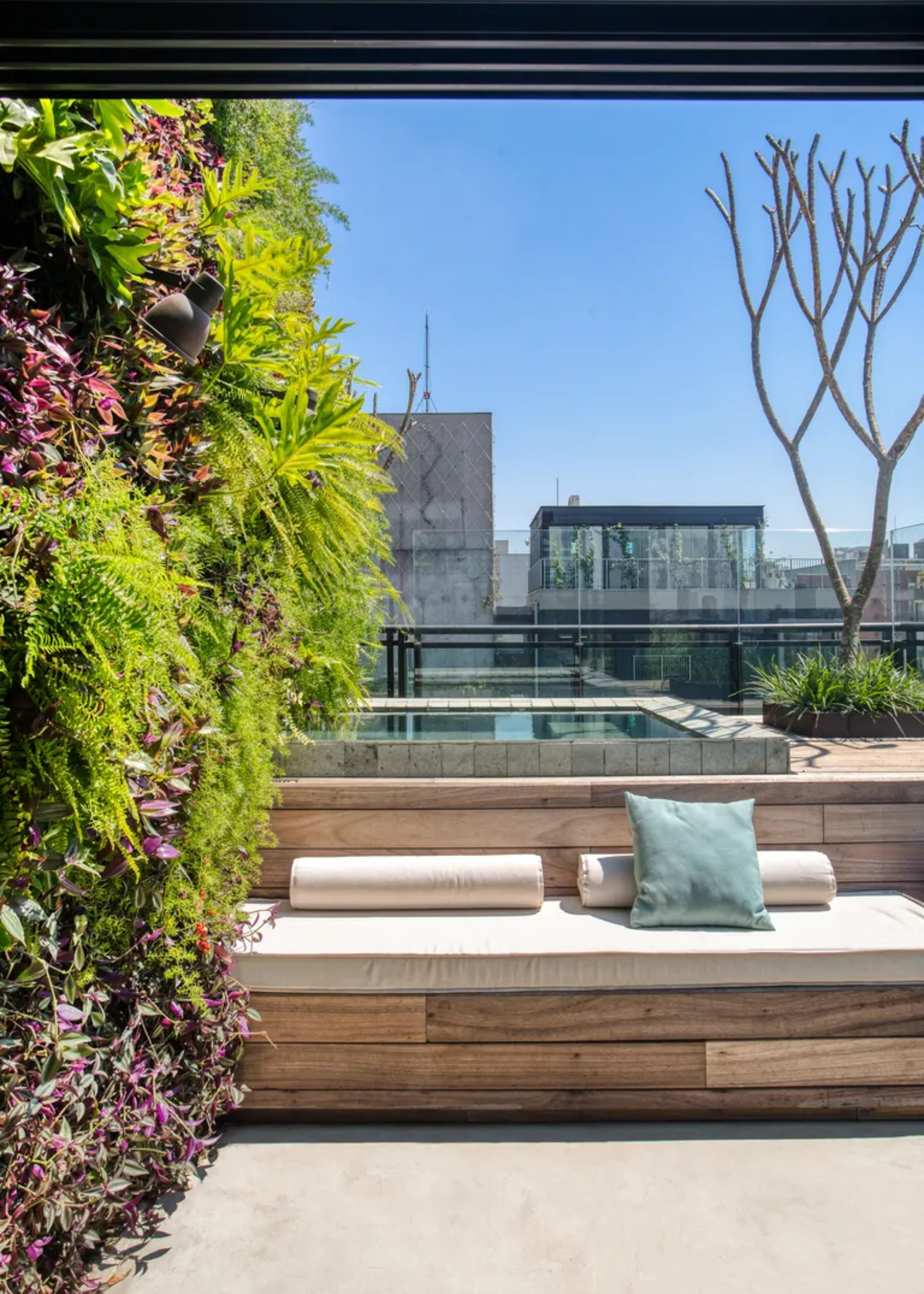 A bright balcony with a living wall and inn-built seating couch