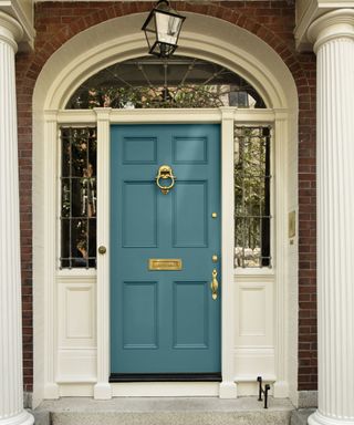 blue front door with brass hardware, brick exterior and white accents