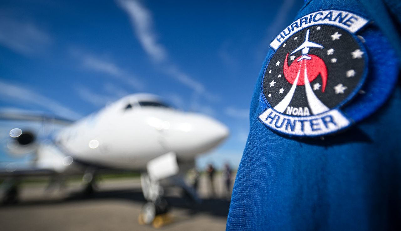 Person wearing a National Oceanic and Atmospheric Administration &quot;Hurricane Hunter&quot; patch with jet in background