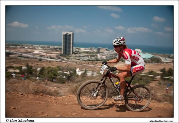 Annika Langvad (Denmark) rides with the skyline of Haifa in the background.