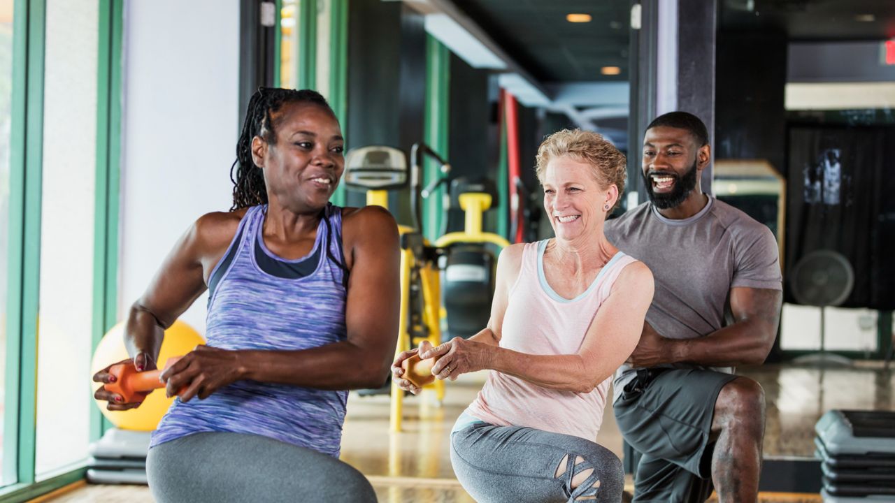 A group of people at the gym performing lunges with rotations