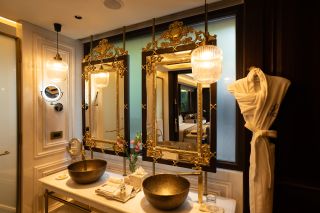 Two gilded mirrors in the bathroom with gold sinks in Arq Pichola of Leela Palace Udaipur