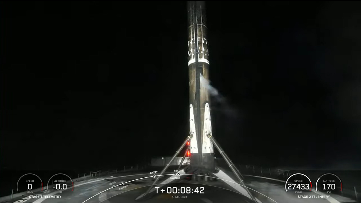 A SpaceX Falcon 9 booster standing atop a drone ship at night