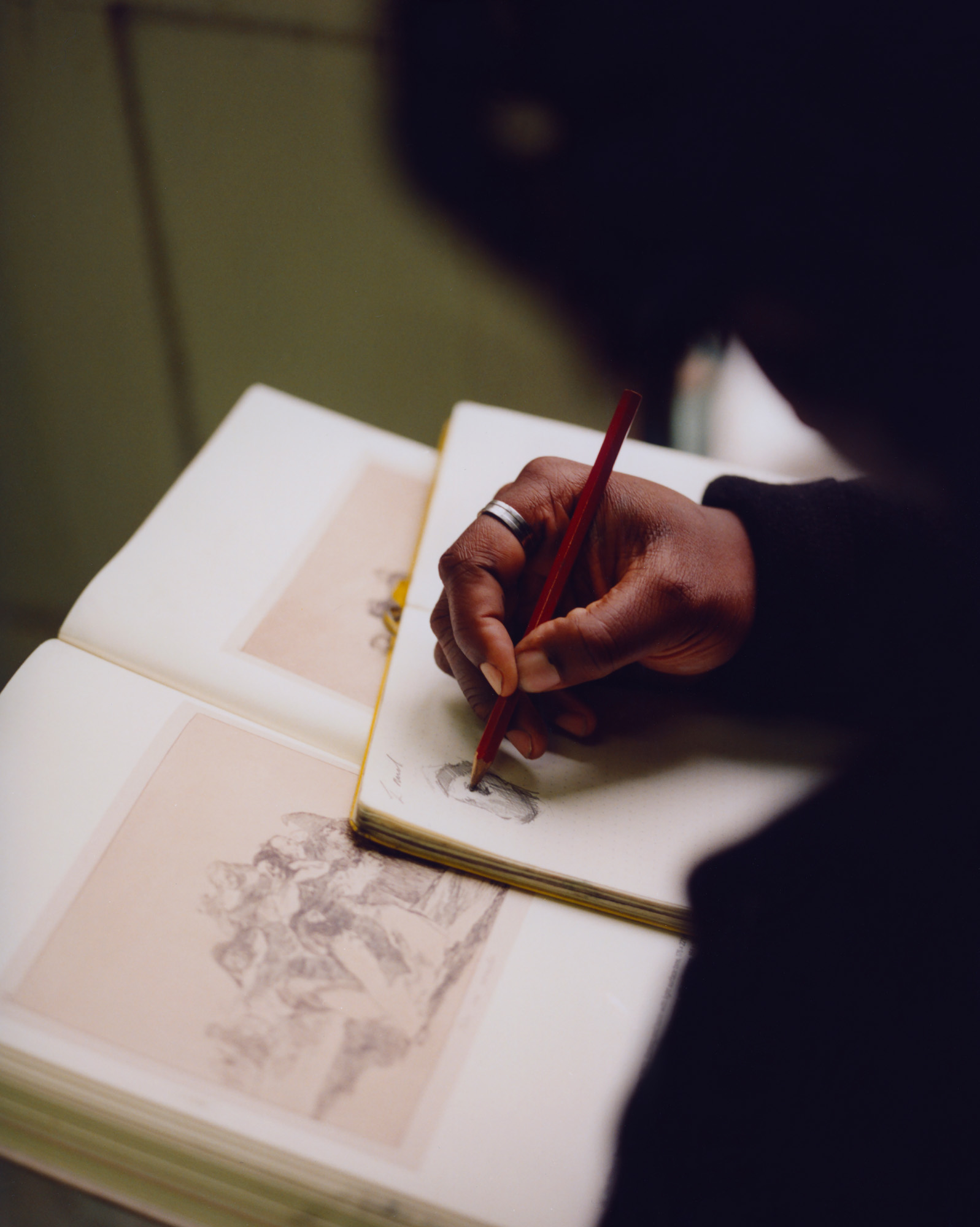 Artist Shaquelle Whyte sketching in a notebook