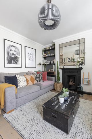 Living room with grey sofa, original fireplace, large mirror and rug