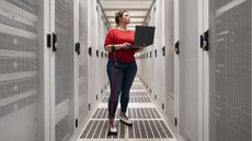 A woman holding a cane works in a data center.