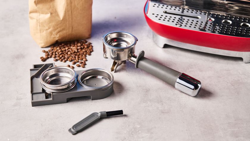 a red smeg espresso machine with burr grinder is photographed against a blue background