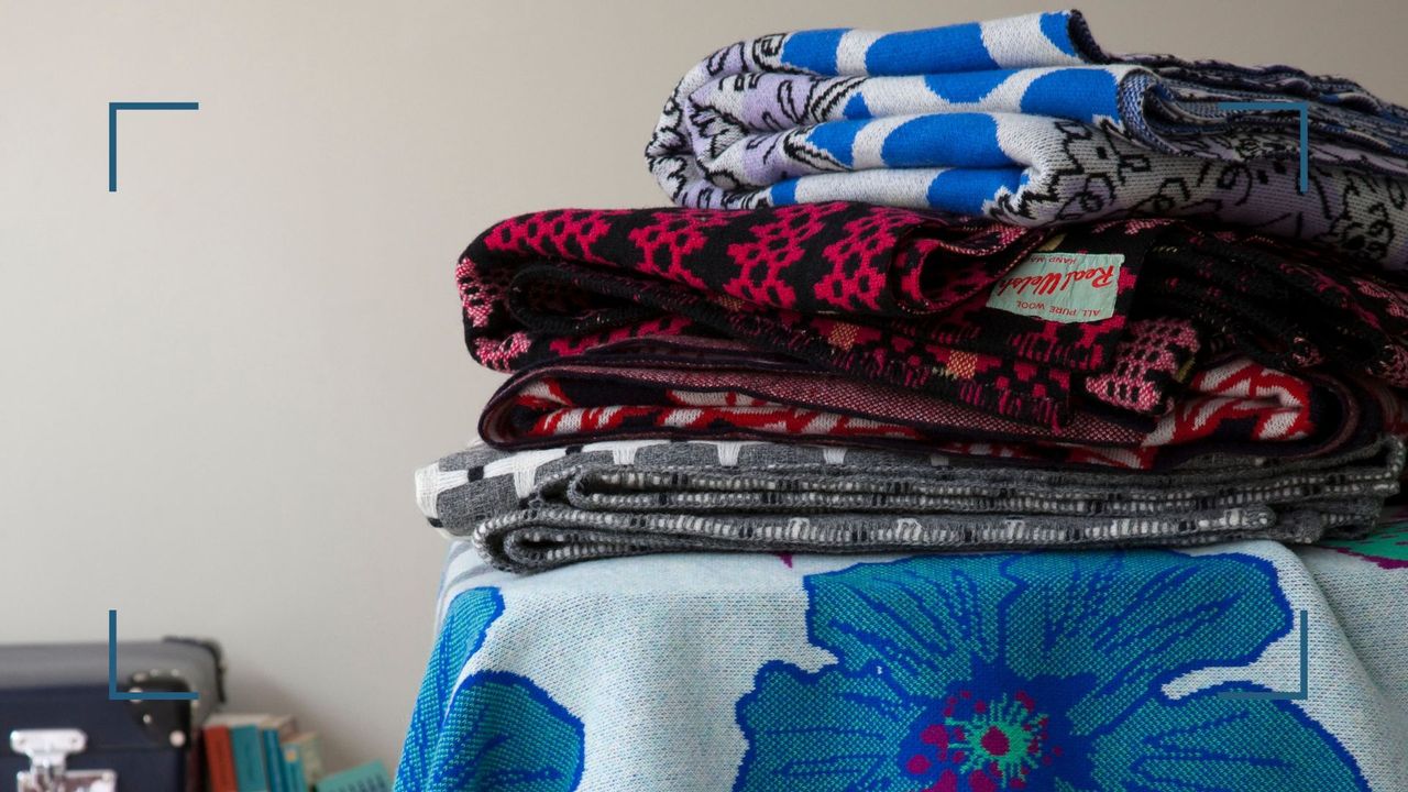 a stack of folded blankets on a bed to support a guide for how to clean a weighted blanket with care