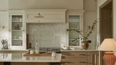 An off-white traditional kitchen by Neptune with a lamp to the light, metro tile backsplash behind the cooker and a pretty frilly pendant light above the island