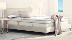 One of the best cooling mattresses, the Saatva Latex Hybrid Mattress, on a bed against a white wall.