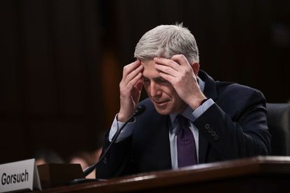 Neil Gorsuch holds his head in his hands.