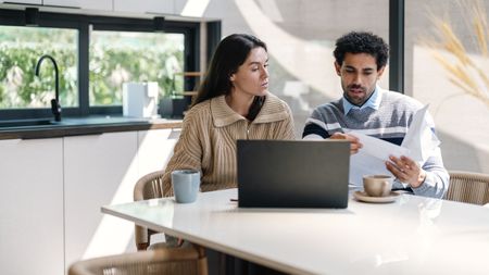 A couple work on financial planning together at their kitchen table.