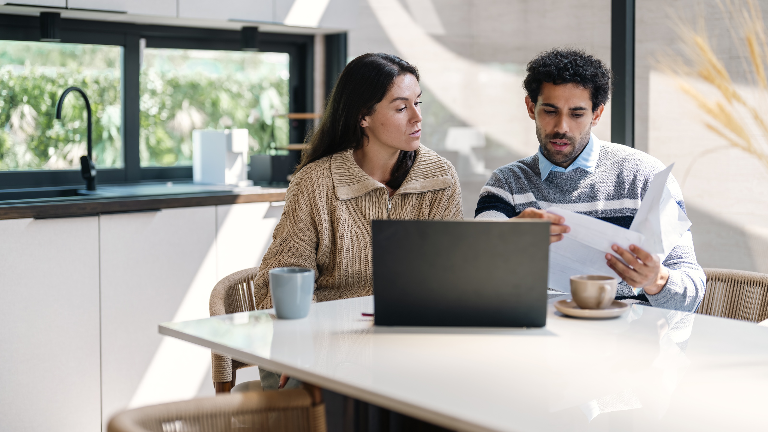 A couple work on financial planning together at their kitchen table.