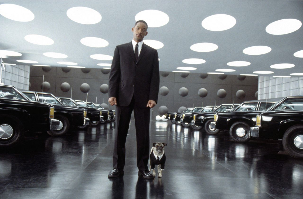 Will Smith&rsquo;s Agent J stands in a futuristic showroom of black cars beside Frank the Pug, who wears a tiny black suit and tie.