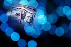 Conceptual pile of American one hundred dollars in glowing lights