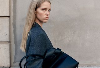 An H&M model carrying a black open-top shopper tote.