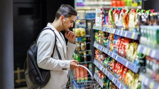 A man stands in a processed food aisle of the grocery store