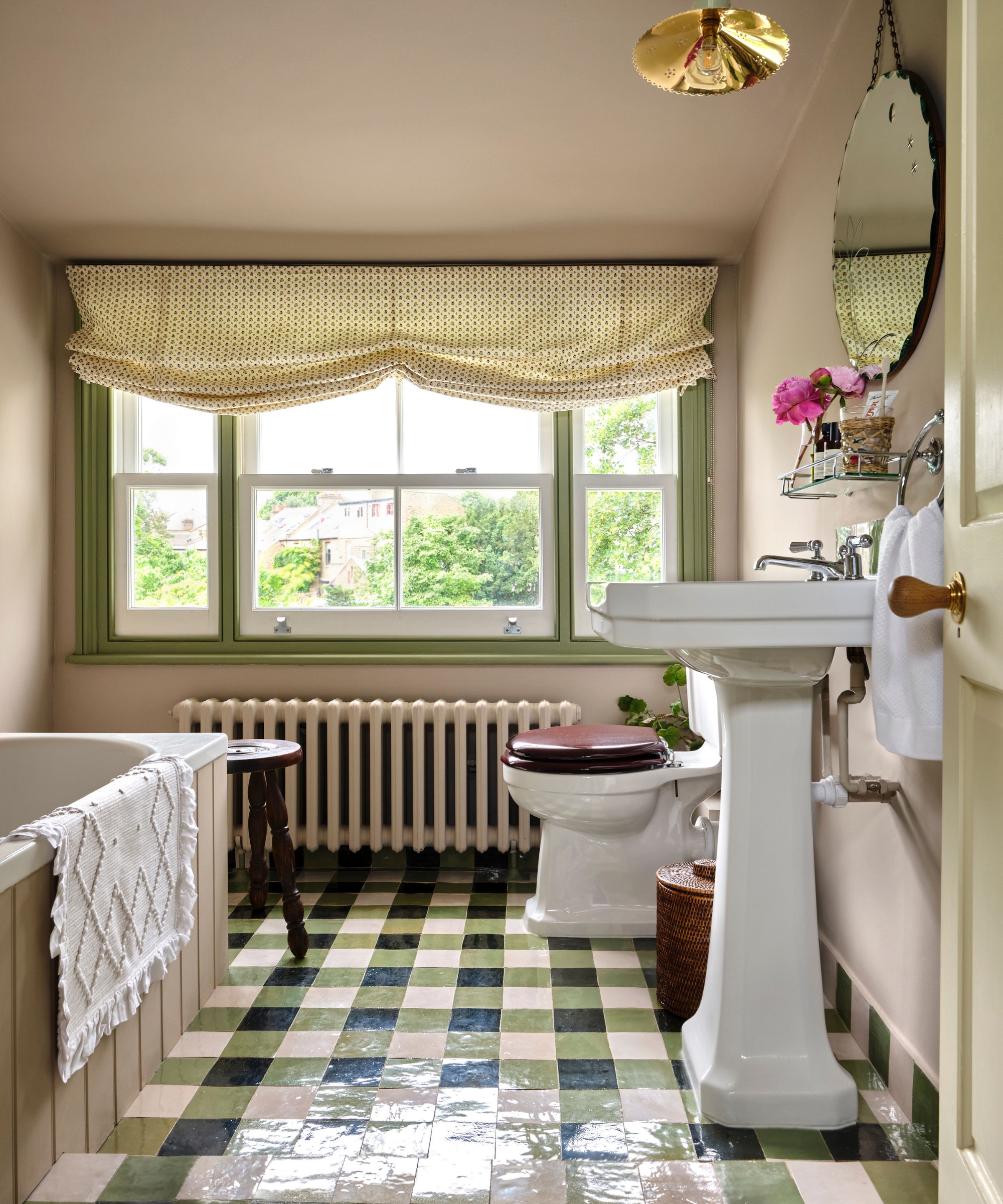 A kids' bathroom with pale pink walls, and green and white gingham floor tiles