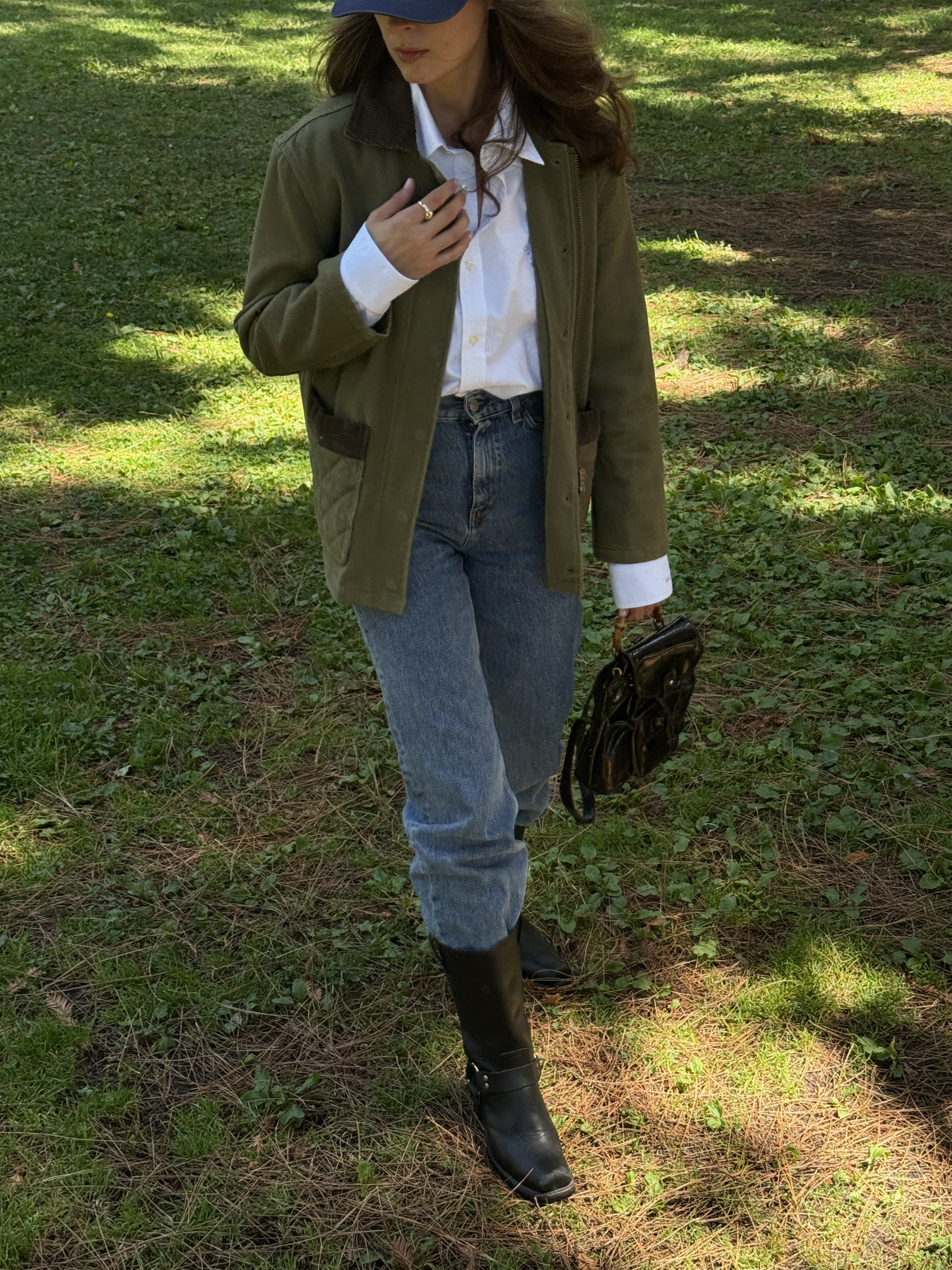 Kathryn Zahorak wearing green jacket, white button down shirt, jeans, and black boots