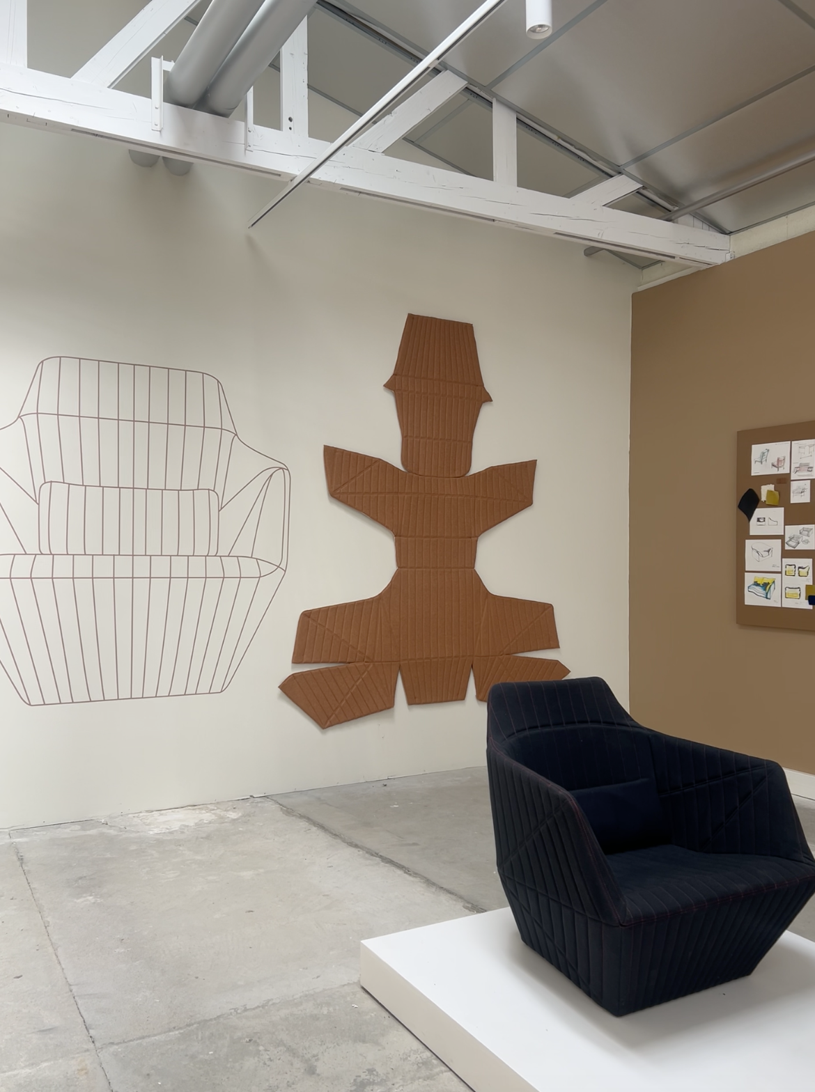 Studio 1860 exhibition displaying the upholstery pattern of a Ligne Roset armchair mounted on the wall, alongside a finished navy upholstered chair.