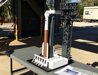 This 3D-printed model of the Atlas V rocket and CST-100 Starliner spacecraft shows how the craft will interface with the Crew Access Tower, Crew Access Arm and White Room (currently shown touching the ship's crew capsule). The whole thing rests under the actual under-construction Crew Access Arm.