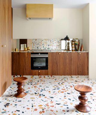 Wooden cabinetry, terrazzo flooring, two wooden stools, coordinating splashback