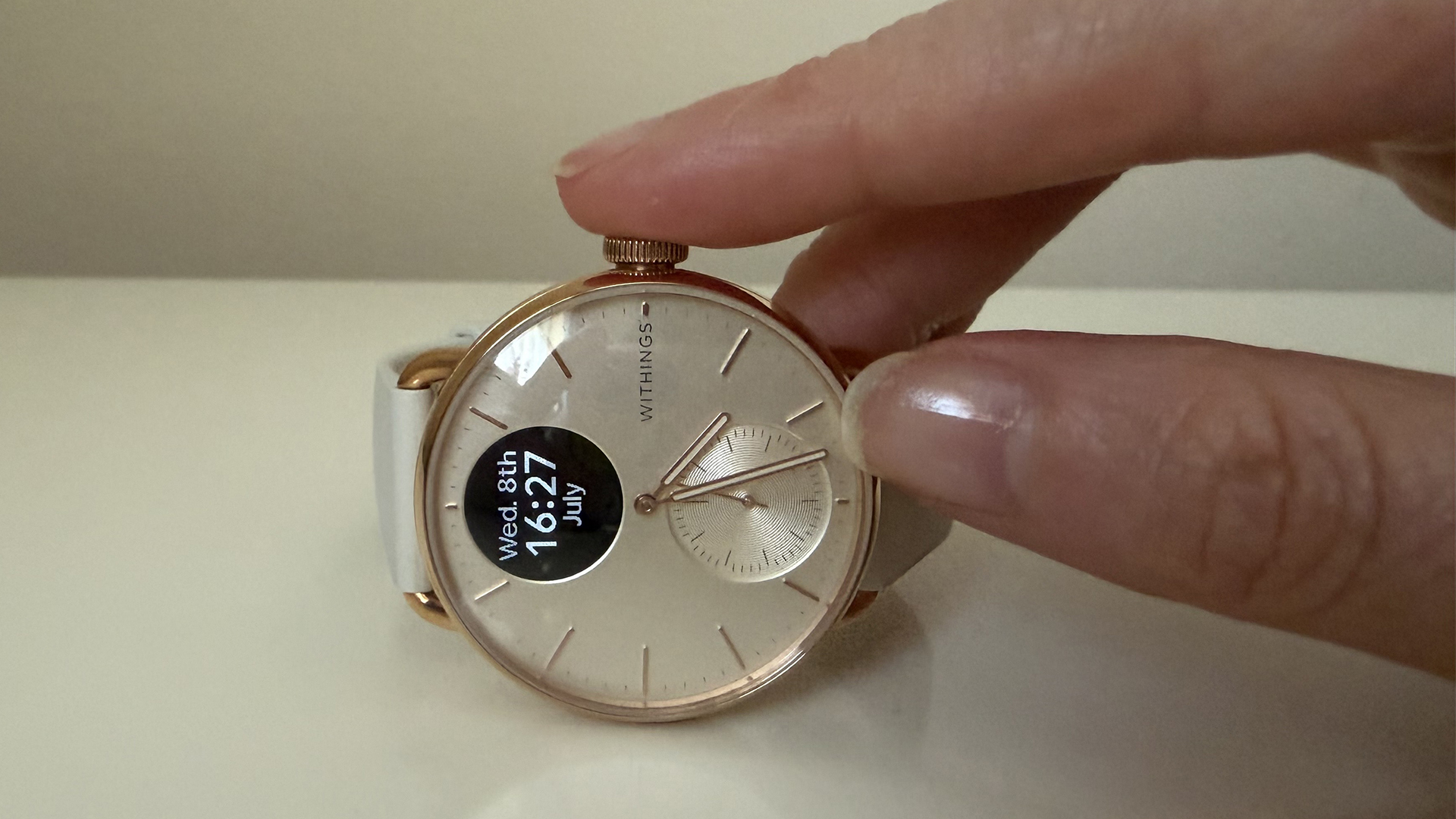 A Closeup of the Withings ScanWatch 2 with a hand pressing the crown to turn the screen on