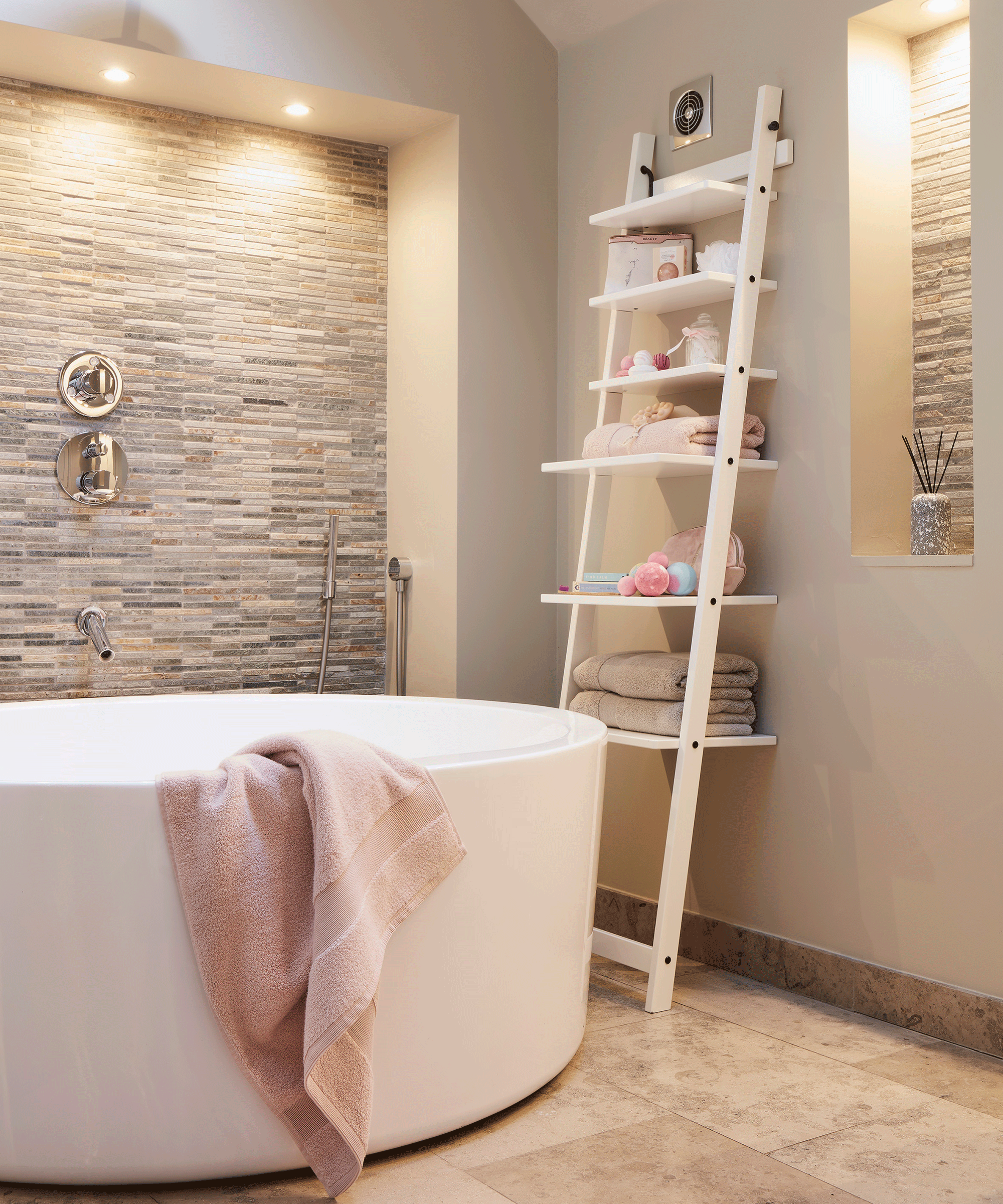 White ladder shelf in bathroom with circular freestanding white enamel bath