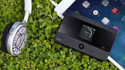 TP-Link M7350 portable Wi-Fi hotspot in use outdoors on some clover