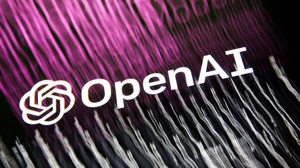 OpenAI&amp;#039;s logo, shot from below against blurred purple and white light streaming off the letters (purple on the left and white on the right)