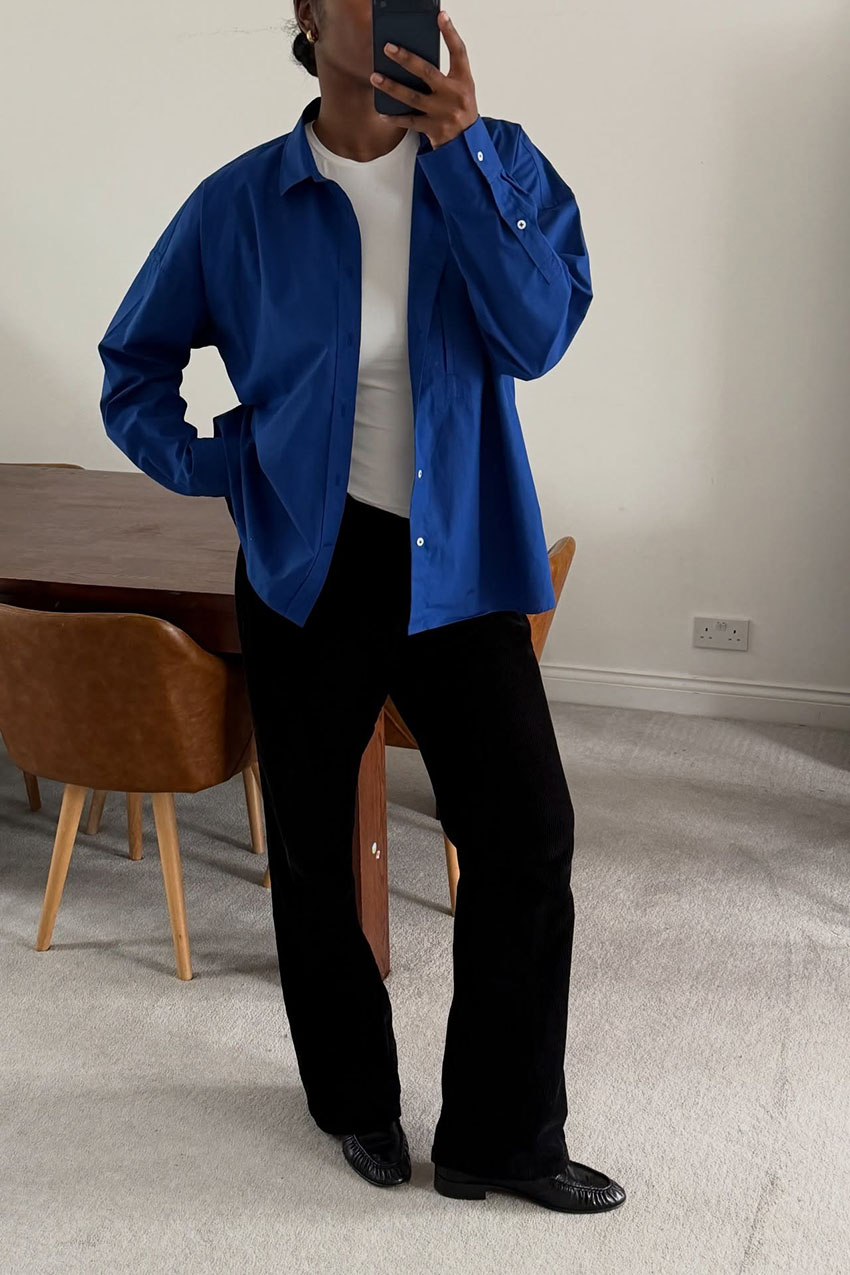 A woman wearing a bright blue button down and black pants.