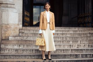 woman in pleated skirt blazer and boots