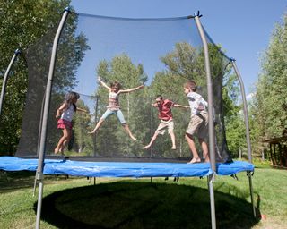 children playing on trampoline in sunny backyard