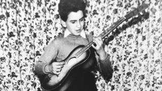 George Harrison of the rock and roll band "The Beatles" poses for a childhood portrait playing an acoustic guitar in circa 1954 in Liverpool, England.