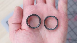 The Luna Ring 2 smart ring on the left and the RingConn 2 smart ring on the right in the palm of a user's hand