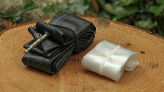 A large black and small white bike inner tube folded side by side on a piece of wood