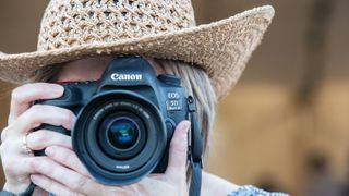 Woman wearing hat holding a Canon EOS 5D Mark IV