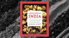 The cover of Madhur Jaffrey's 'Vegetarian India' on a background of close-up photo of spices common to Indian cooking.