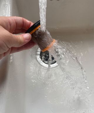 washing Shark Cordless Handheld Vacuum WV200UK filter under running water in a white sink