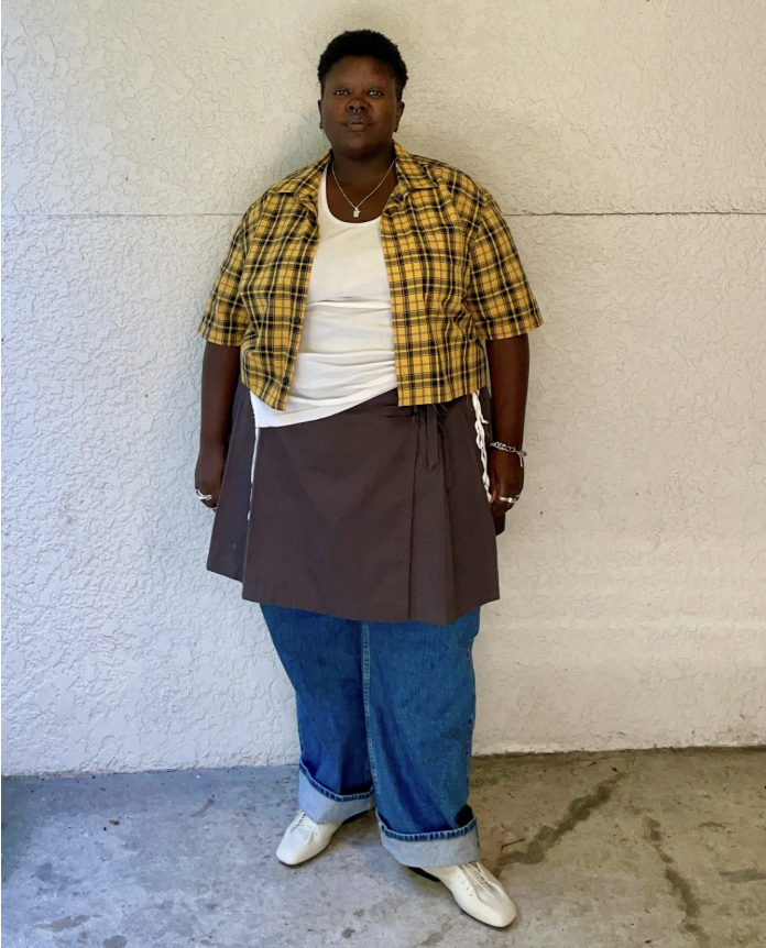 Lydia Okello wearing a plaid shirt with a skirt over jeans