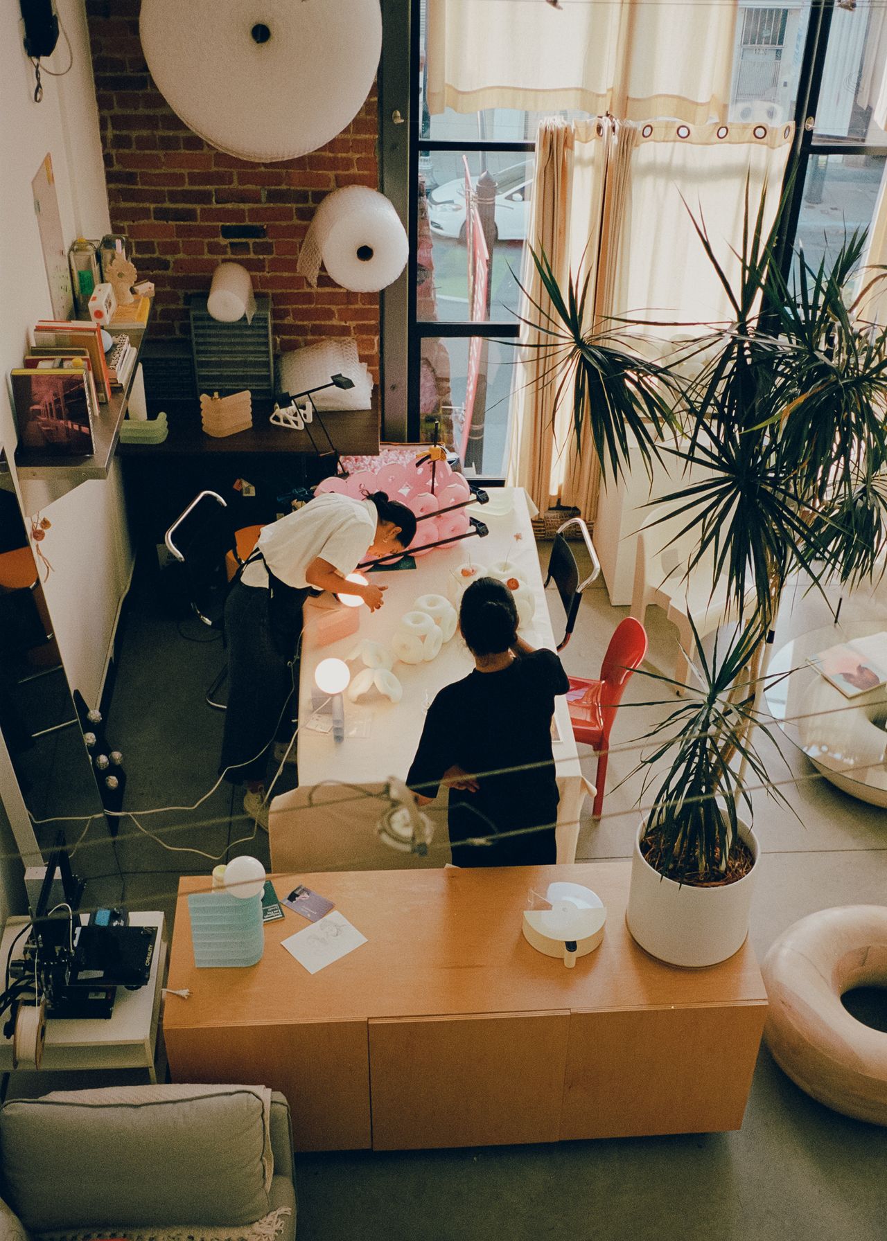 Two young artisans at work in their creations-filled, naturally lit studio.