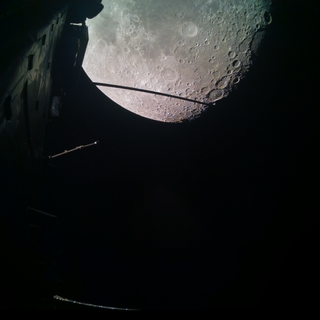 cylindrical spacecraft components in front of the cratered grey surface of the moon