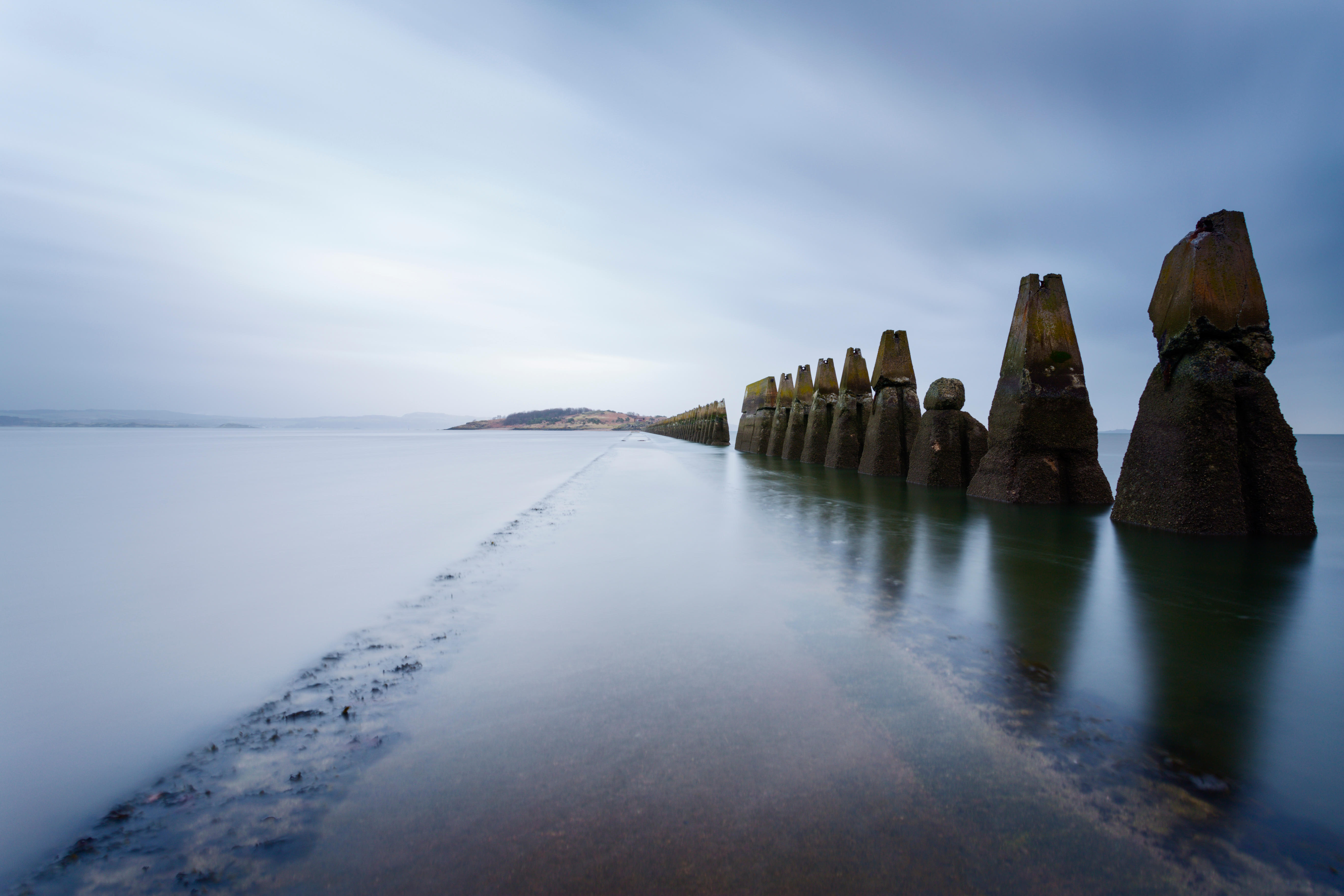 A causeway flanked by large rock structures with the sea coming in